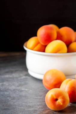 Olgun kayısı bir kase. Koyu arka plan. Bir vegan yemek ve bir