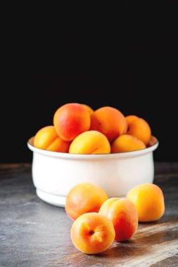 Olgun kayısı bir kase. Koyu arka plan. Bir vegan yemek ve bir