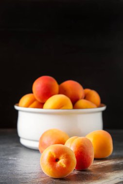 Olgun kayısı bir kase. Koyu arka plan. Bir vegan yemek ve bir