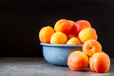 Olgun kayısı bir kase. Koyu arka plan. Bir vegan yemek ve bir