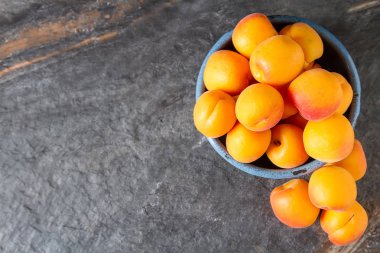 Olgun kayısı bir kase. Koyu arka plan. Bir vegan yemek ve bir