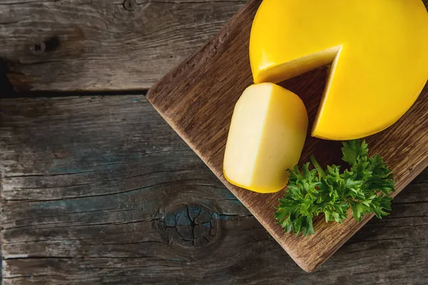 Yuvarlak gouda peyniri maydanoz ile. Koyu arka plan.