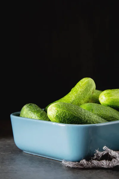 Pepinos frescos en un tazón azul. Fondo oscuro. Comida saludable, un —  Fotos de Stock