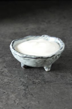 Ev yapımı ekşi krema bir seramik kase. Koyu arka plan.