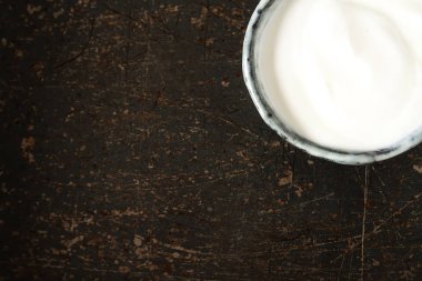 Ev yapımı ekşi krema bir seramik kase. Koyu arka plan.