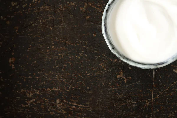 Ev yapımı ekşi krema bir seramik kase. Koyu arka plan.