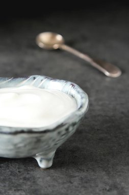 Homemade sour cream in a ceramic bowl. Dark background.