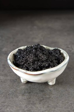 Seramik bir kabın içinde siyah mersin balığı havyar. Koyu arka plan.