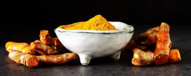 Zerdeçal tozu ve taze zerdeçal. Koyu arka plan. T için alan