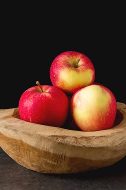 Ahşap bir kase içinde olgunlaşmış sulu elma. Koyu arka plan. Te için alan