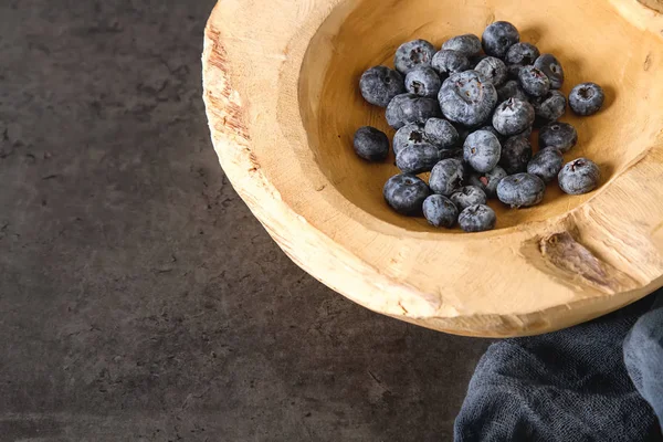 Ahşap bir kabın içinde olgunlaşmış sulu yaban mersini. Koyu arka plan. Uzay 