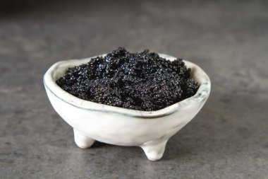 Seramik bir kabın içinde siyah mersin balığı havyar. Koyu arka plan.