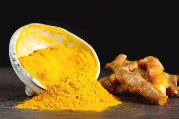 Zerdeçal tozu ve taze zerdeçal. Koyu arka plan. T için alan