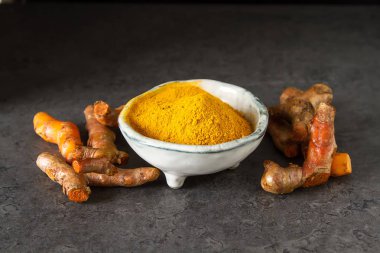 Zerdeçal tozu ve taze zerdeçal. Koyu arka plan. T için alan