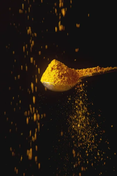 黄姜黄的金属勺子。下降的香料。黑色背景 — 图库照片
