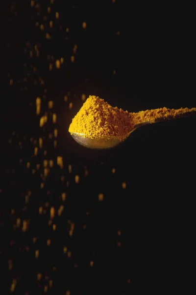 黄姜黄的金属勺子。下降的香料。黑色背景 — 图库照片