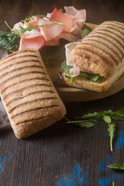 Baguete francesa com salsicha, tomate e alface. Backgro escuro — Fotografia de Stock