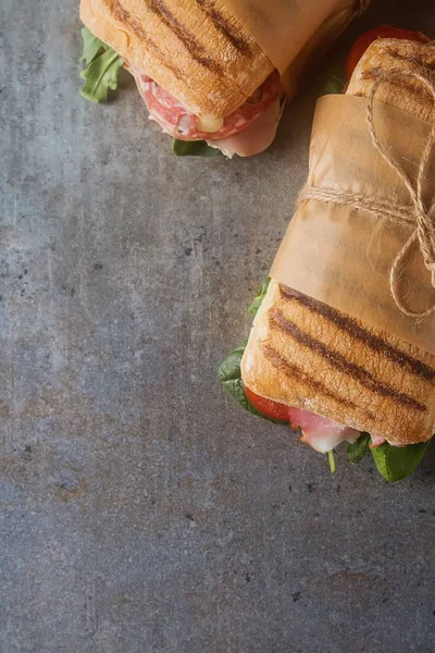 Baguette alla francese con salsiccia, pomodori e lattuga. Backgro scuro — Foto Stock