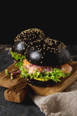 Somon Balık, marul, hardal ile siyah burger. Koyu arka plan