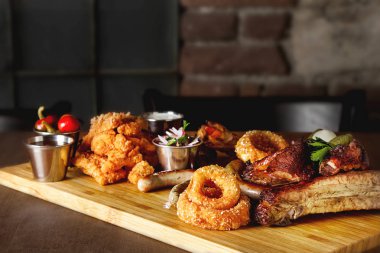 Et ürün çeşitliliği, tavuk kanadı, sosis, soğan halkaları, soslar. Ahşap arka plan. Restoranın fotoğraf