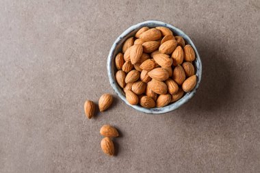 Soyulmuş badem bir seramik tabak içinde. Koyu gri arka plan.