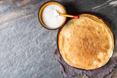 Ekşi krema ile ahşap bir tabakta krep yığını. Geleneksel