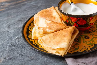 Ekşi krema ile bir tabakta krep yığını. Geleneksel th için