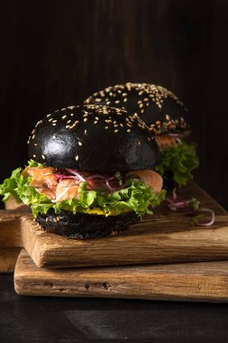 Somon Balık, marul, hardal ile siyah burger. Koyu arka plan