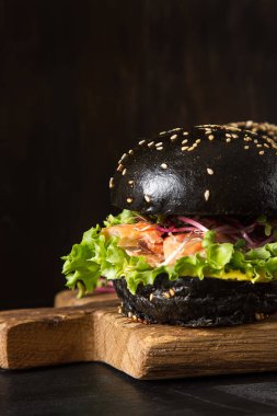 Somon Balık, marul, hardal ile siyah burger. Koyu arka plan