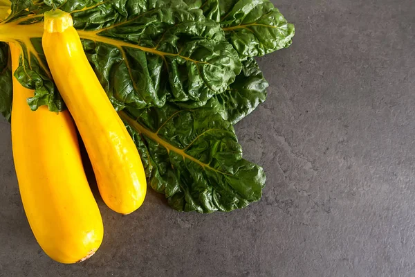 Yellow zucchini, chard. Dark background. Vegetarian food from th — Stock Photo, Image