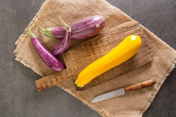 Small eggplant, yellow zucchini Dark background. Vegetarian food