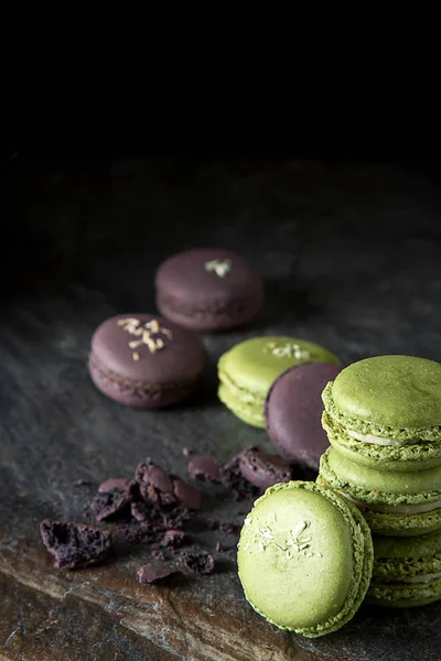 French dessert macaroons with pistachios and strawberries. Dark background.