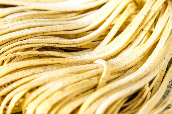 Hausgemachte italienische Tagliatelle mit Mehl. dunkler Hintergrund. — Stockfoto