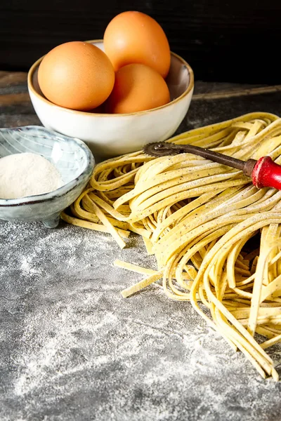 Hausgemachte italienische Tagliatelle mit Mehl. dunkler Hintergrund. — Stockfoto
