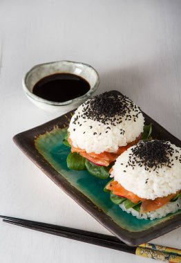 Somon füme, yeşil salata ve soya sosu ile pirinç suşi-hamburger. Modern sağlıklı gıda. Açık renkli