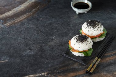 Somon füme, yeşil salata ve soya sosu ile pirinç suşi-hamburger. Modern sağlıklı gıda. Koyu arka plan