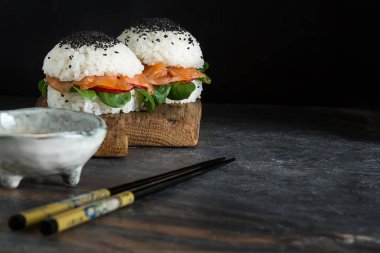 Somon füme, yeşil salata ve soya sosu ile pirinç suşi-hamburger. Modern sağlıklı gıda. Koyu arka plan