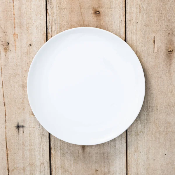 Белая пустая тарелка на старом деревянном фоне. Вид сверху с копией s — стоковое фото