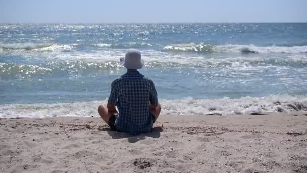 Homme assis sur le rivage de la mer — Video