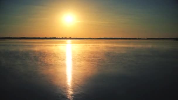 Time lapse du soleil se levant sur l'eau à l'aube avec la brume du matin — Video