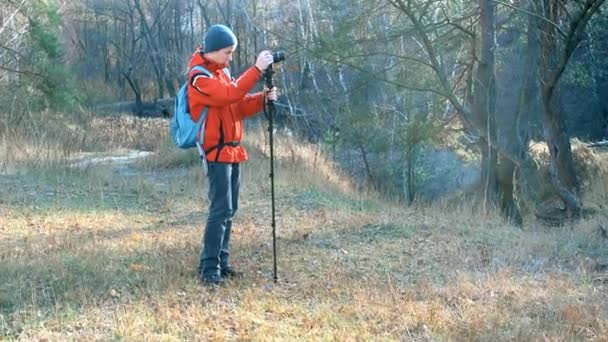 Adolescente filmando en un DSLR y monópodo en bosque otoñal . — Vídeo de stock