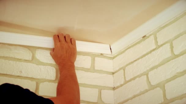 Artesano montando una moldura de techo blanco — Vídeo de stock
