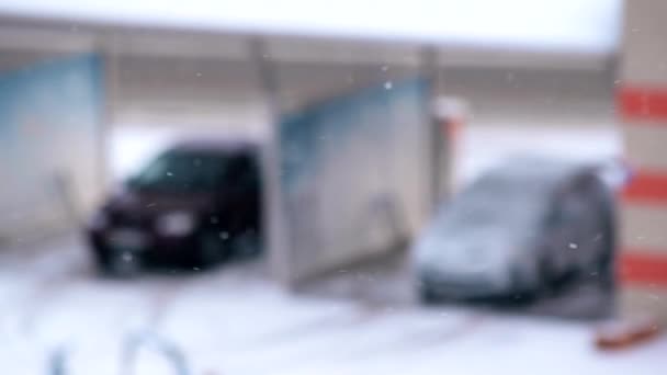 Sneeuw valt op onscherpe achtergrond met auto 's — Stockvideo