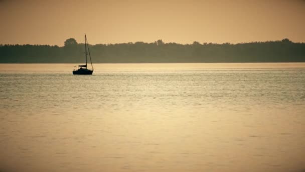 Silhueta barco à vela longe em um lago ou rio — Vídeo de Stock