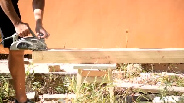 Плотник строит деревянную балку с помощью электрического инструмента для облицовки древесины — стоковое видео
