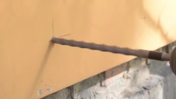 Arbetstagaren gör ett hål i en vägg med en perforator — Stockvideo