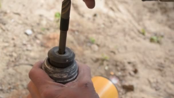 Manos de un trabajador insertando una broca en el perforador al aire libre — Vídeo de stock