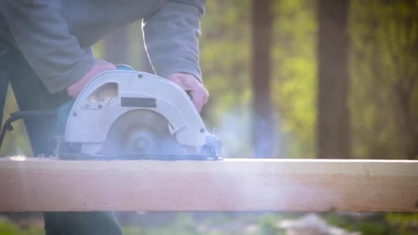 Распиливание деревянного бревна с помощью циркулярной ручной пилы — стоковое видео