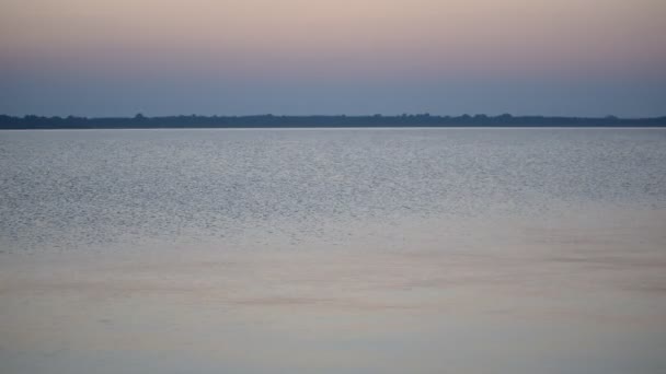 Спокійна водна поверхня озера або річки в сутінках з барвистим небом — стокове відео