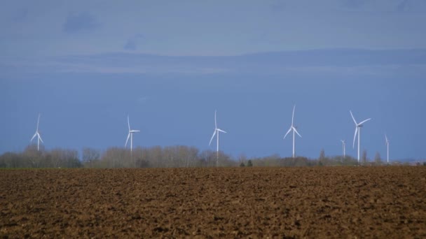 Обертаються турбіни на вітряному полі на фоні блакитного неба — стокове відео